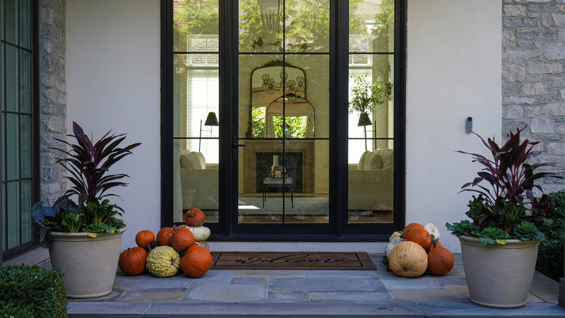 Heirloom pumpkins styled at a modern glass-door entry — Fall Into Pumpkins